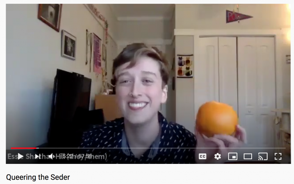 a screenshot of a paused YouTube video which shows a person in a patterned shirt holding an orange