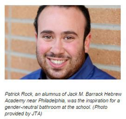 Image of Patrick Rock in front of a brick wall. He is wearing a blue shirt and smiling at the camera.