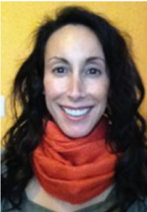 Image of Michelle Tirella-Ventura, wearing a red scarf and standing in front of a yellow wall.