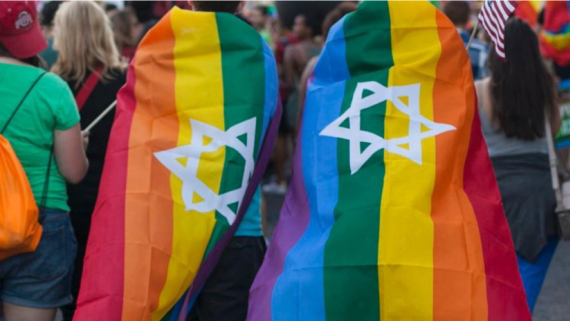 Image of two people wrapped in rainbow LGBTQ Pride flags with the Star of David on them.