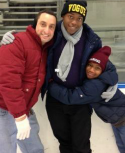 Image of James Cohen with his two sons at an ice skating rink. They have their arms around each other and are smiling.