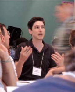 Image of Gregg Drinkwater gesturing with his hands while explaining something to people seated in front of him.