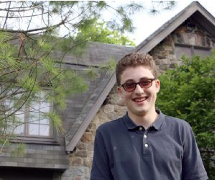 Image of Benjamin standing outside the Westchester synagogue. He is wearing sunglasses and smiling.