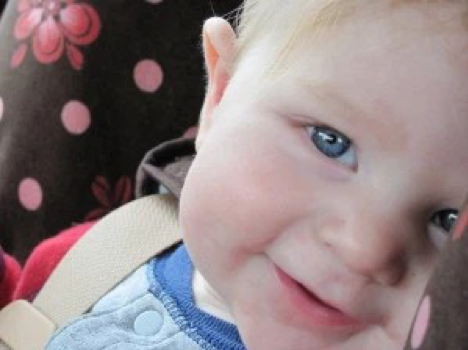 Image of a baby with blue eyes and blond hair smiling.