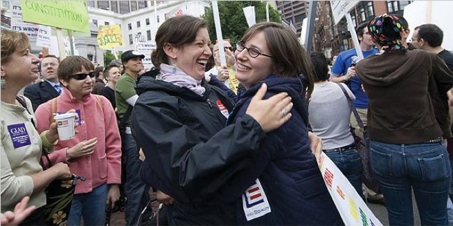 Image of Leah Krieger and Orly Jacobovits celebrating outside the Massachusetts State House with a crowd of people.