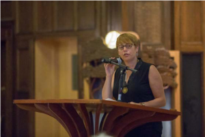 Image of Idit Klein speaking at a podium.