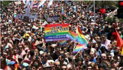 Image of a rainbow LGBT flag with Hebrew writing on it in a large crowd of people.