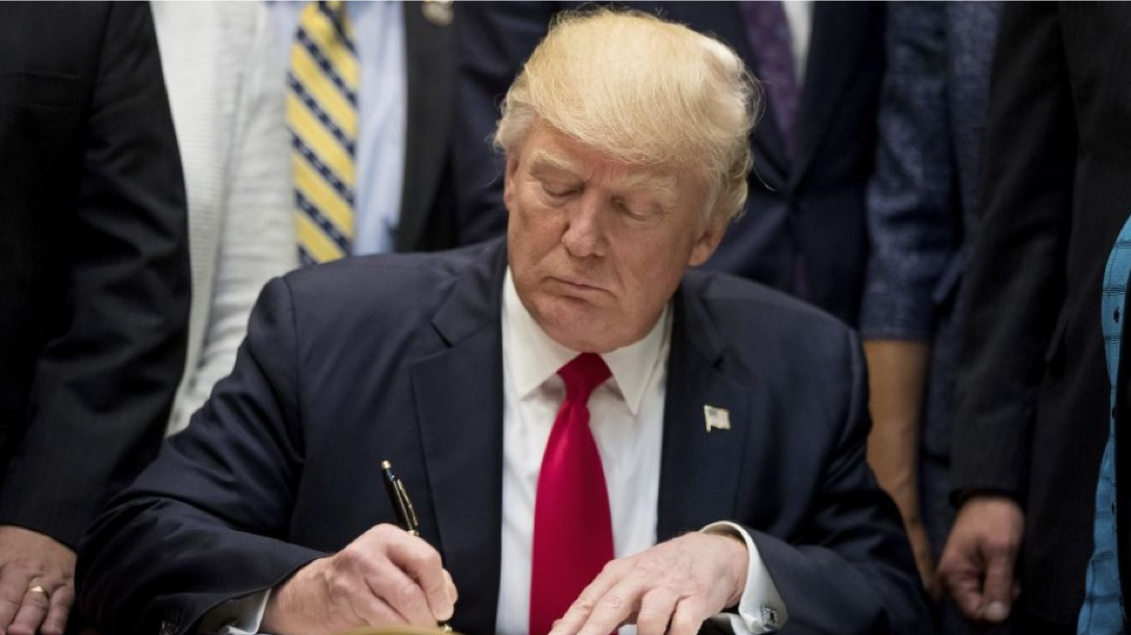 Image of President Donald Trump signing a paper.