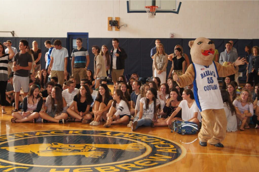Image of a large group of teenagers in a gymnasium, along with a person dressed up as a lion as a mascot.