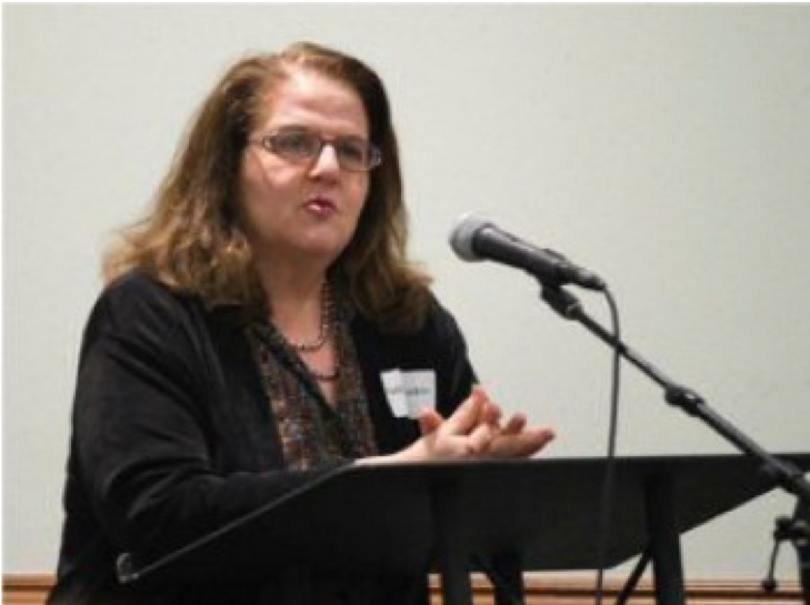 Image of Rabbi Gila RuskinBeth speaking in front of a podium.