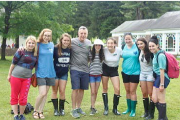 Image of a group of people standing with their arms around each other outside.