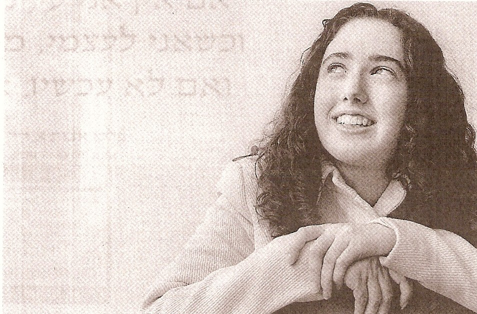 Image of Shulamit Izen in front of a backdrop of Hebrew writing.