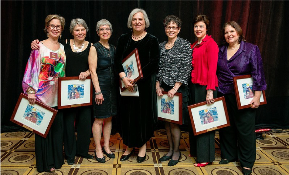 Image of the seven mothers who founded Keshet’s Parent & Family Connection, standing together and holding framed pictures.