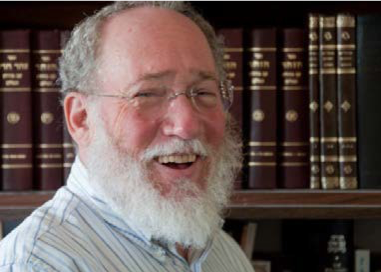 Image of Rabbi Daniel Landes standing in front of a bookshelf and smiling.
