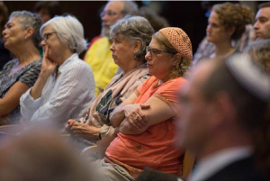 Image of a group of people gathered at Boston's Israel Temple. They are all sitting and looking forward.