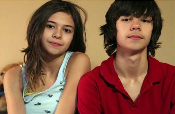 Image of Nicole and her brother. Nicole is wearing a blue tank top and her brother is wearing a red shirt.