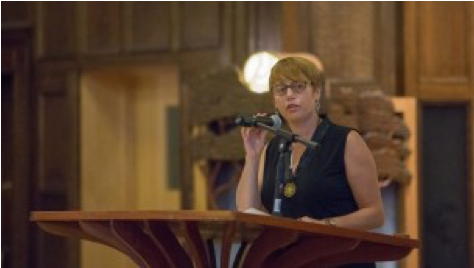 Image of Idit Klein speaking at a podium.