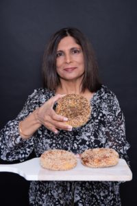 Shulie Madnick holding up a bagel