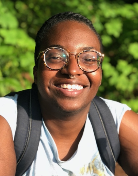 A black person wearing glasses, smiling at the camera