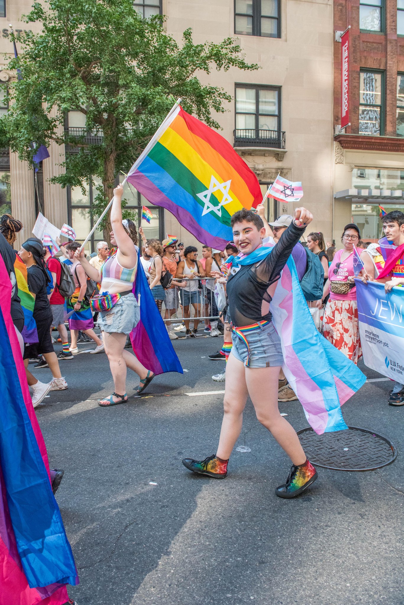 A group of people in a parade with rainbow flags with Stars of David on them.